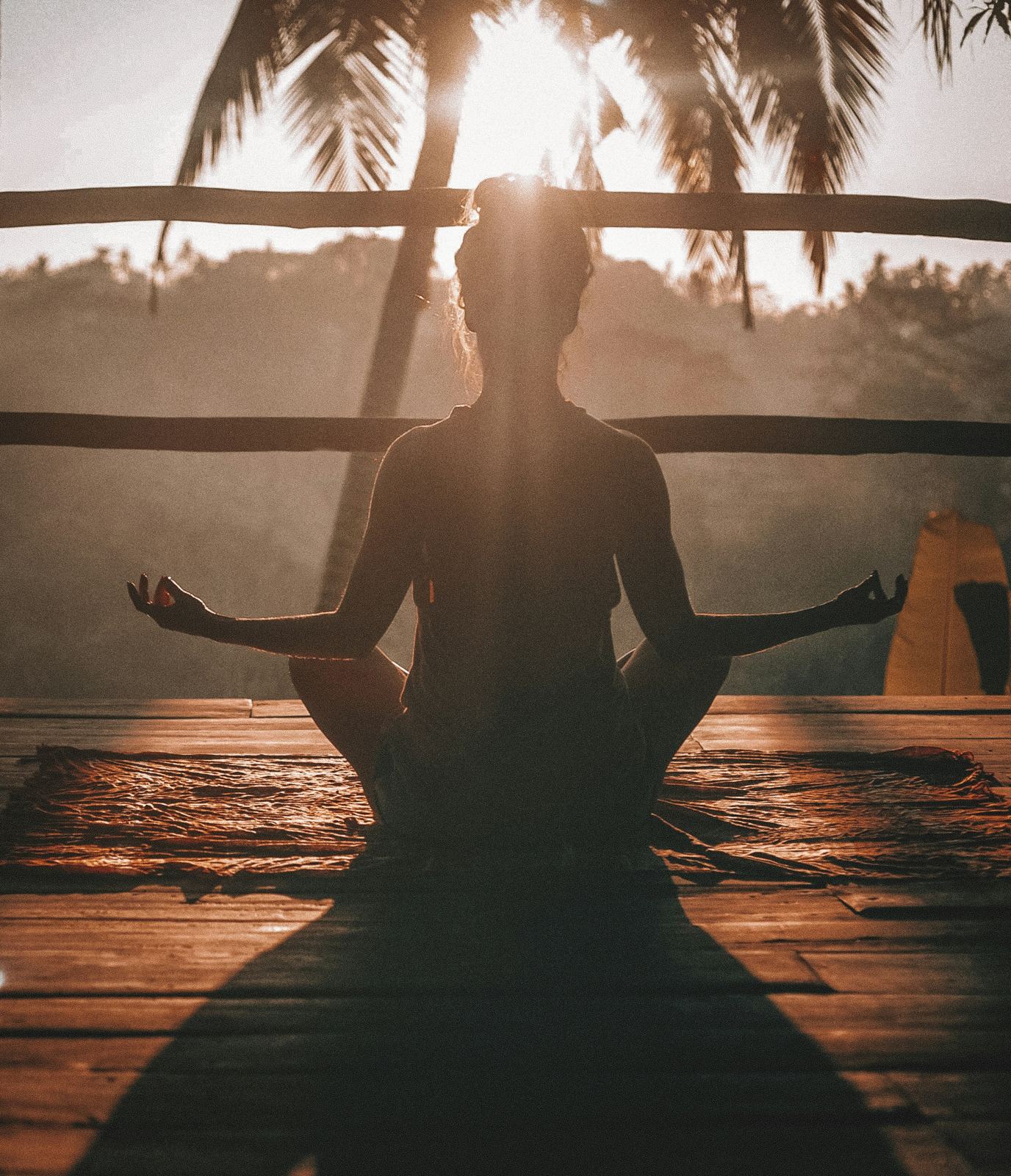 Pessoa meditando ao amanhecer, em posição de lótus